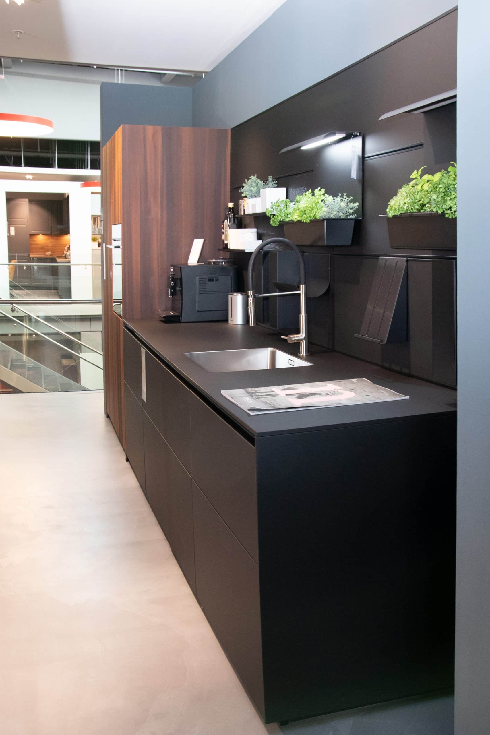 Elegante Einbauküche: NX 870 Front in Onyxschwarz feinmatt, harmonisch kombiniert mit Lärche geräuchert. Diese Küche vereint modernes Design mit natürlicher Wärme. Mit individuellen Anpassungsmöglichkeiten an Ihre Räumlichkeiten wird diese Küche zum Herzstück Ihres Zuhauses. Entdecken Sie zeitlose Schönheit und Funktionalität in einer Einbauküche, die Ihre Bedürfnisse erfüllt.