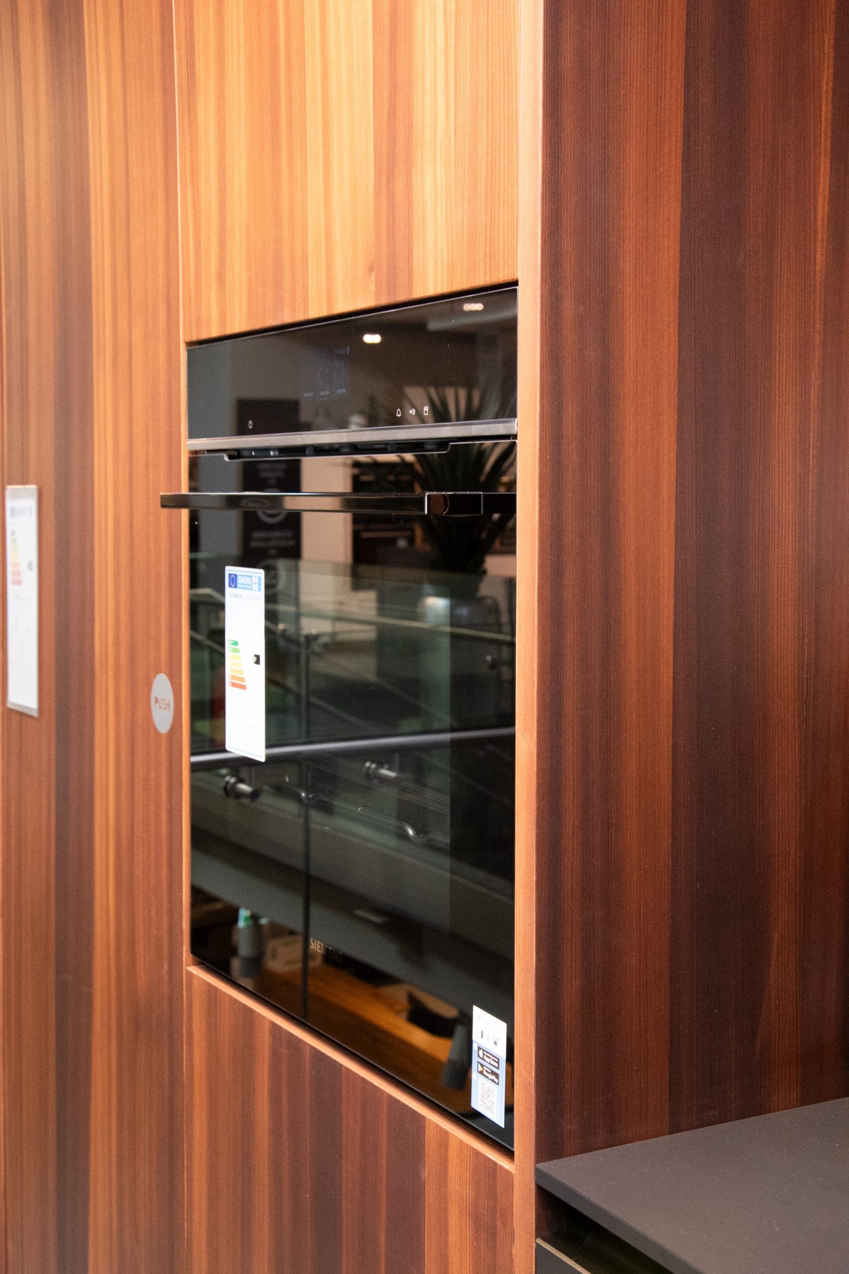 Elegante Einbauküche: NX 870 Front in Onyxschwarz feinmatt, harmonisch kombiniert mit Lärche geräuchert. Diese Küche vereint modernes Design mit natürlicher Wärme. Mit individuellen Anpassungsmöglichkeiten an Ihre Räumlichkeiten wird diese Küche zum Herzstück Ihres Zuhauses. Entdecken Sie zeitlose Schönheit und Funktionalität in einer Einbauküche, die Ihre Bedürfnisse erfüllt.