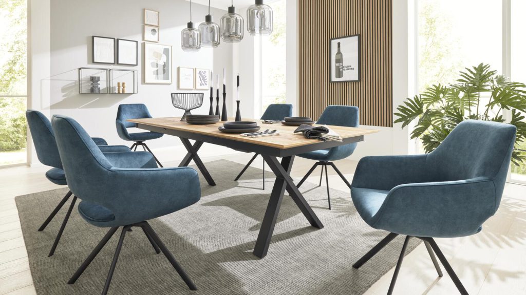 Modernes Esszimmer mit Holztisch, sechs blauen Stühlen und minimalistischer Einrichtung mit gerahmter Kunst und Hängelampen.