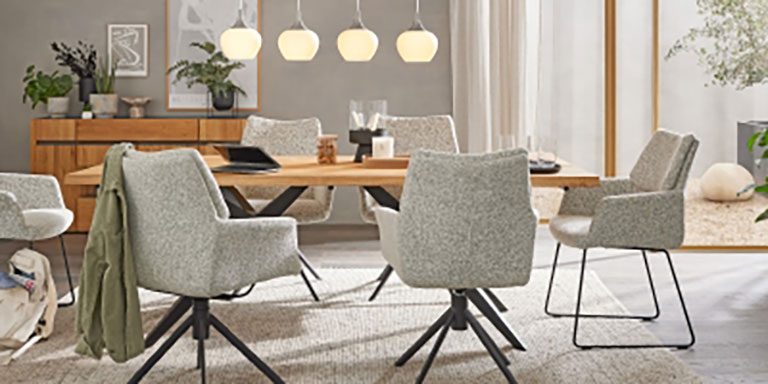 Modernes Esszimmer mit Holztisch, sechs grauen gepolsterten Stühlen, Pendelleuchten und minimalistischem Dekor.