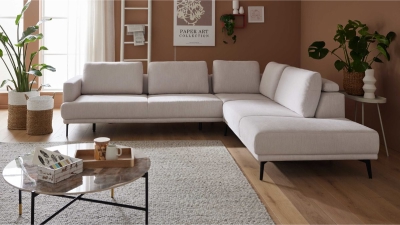 Modernes Wohnzimmer mit einem weißen Sektionssofa, einem runden Couchtisch und Zimmerpflanzen auf einer braunen Akzentwand.