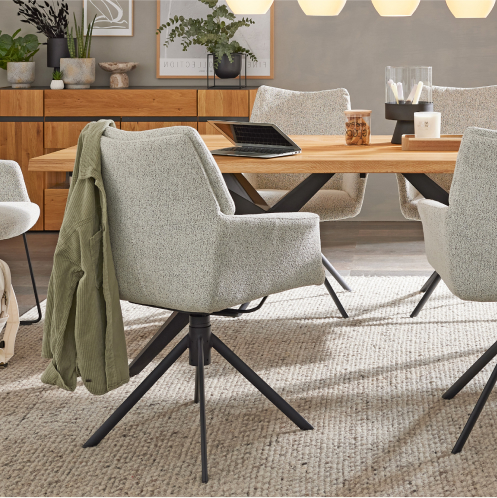 Modernes Esszimmer mit hellgrauen Stühlen, Holztisch, Laptop und einer grünen Jacke, die über einen Stuhl drapiert ist.