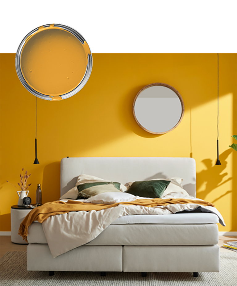 Ein gemütliches Schlafzimmer mit einem beigen Bett und einer leuchtend gelb gestrichenen Wand, die mit einem runden Spiegel und Hängelampen ausgestattet ist.