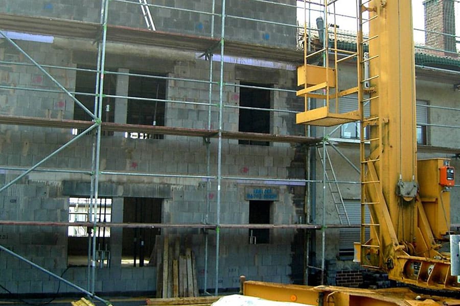 Teilweise errichtetes Gebäude mit Gerüsten und Baugeräten im Vordergrund.