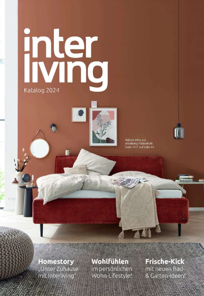 Ein modernes Wohnzimmer mit einem roten Schlafsofa, neutraler Einrichtung und dem Text interliving Katalog 2024 an einer braunen Wand.