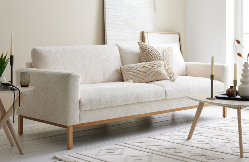 Cremefarbenes Sofa mit strukturierten Kissen in einem modernen Wohnzimmer mit neutralem Dekor und natürlichem Licht.