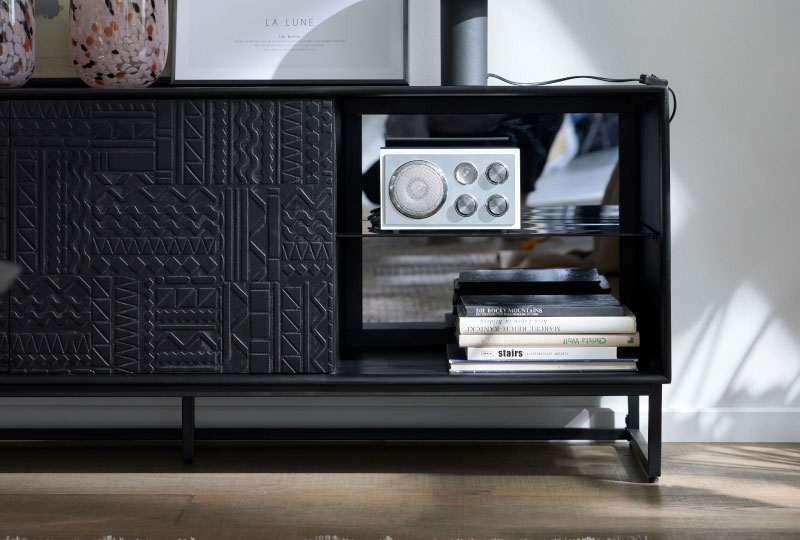 Ein altes Radio steht auf einem Regal neben gestapelten Büchern in einem modernen schwarzen Schrank.