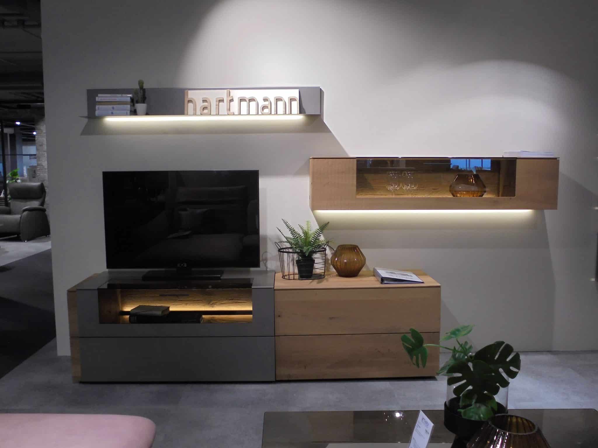 Modernes Wohnzimmer mit dem Wohnprogramm Vara TV-Element, Regalen, Deko-Akzenten und Pflanzen vor einer hellen Wand.