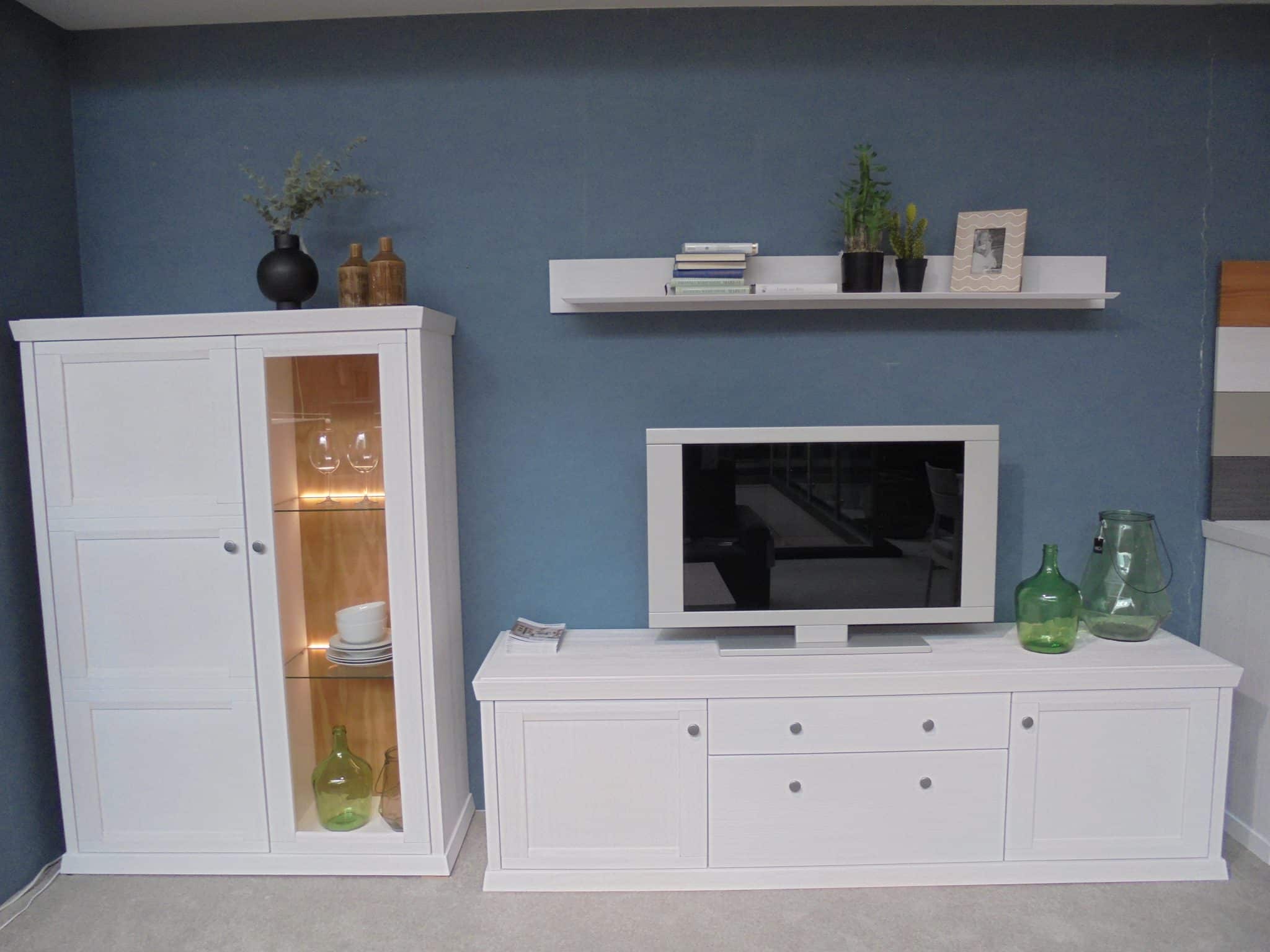 Modernes Wohnzimmer mit dem Wohnprogramm WM Casa 220 mit weißen Schränken, TV und grünen Glasvasen.