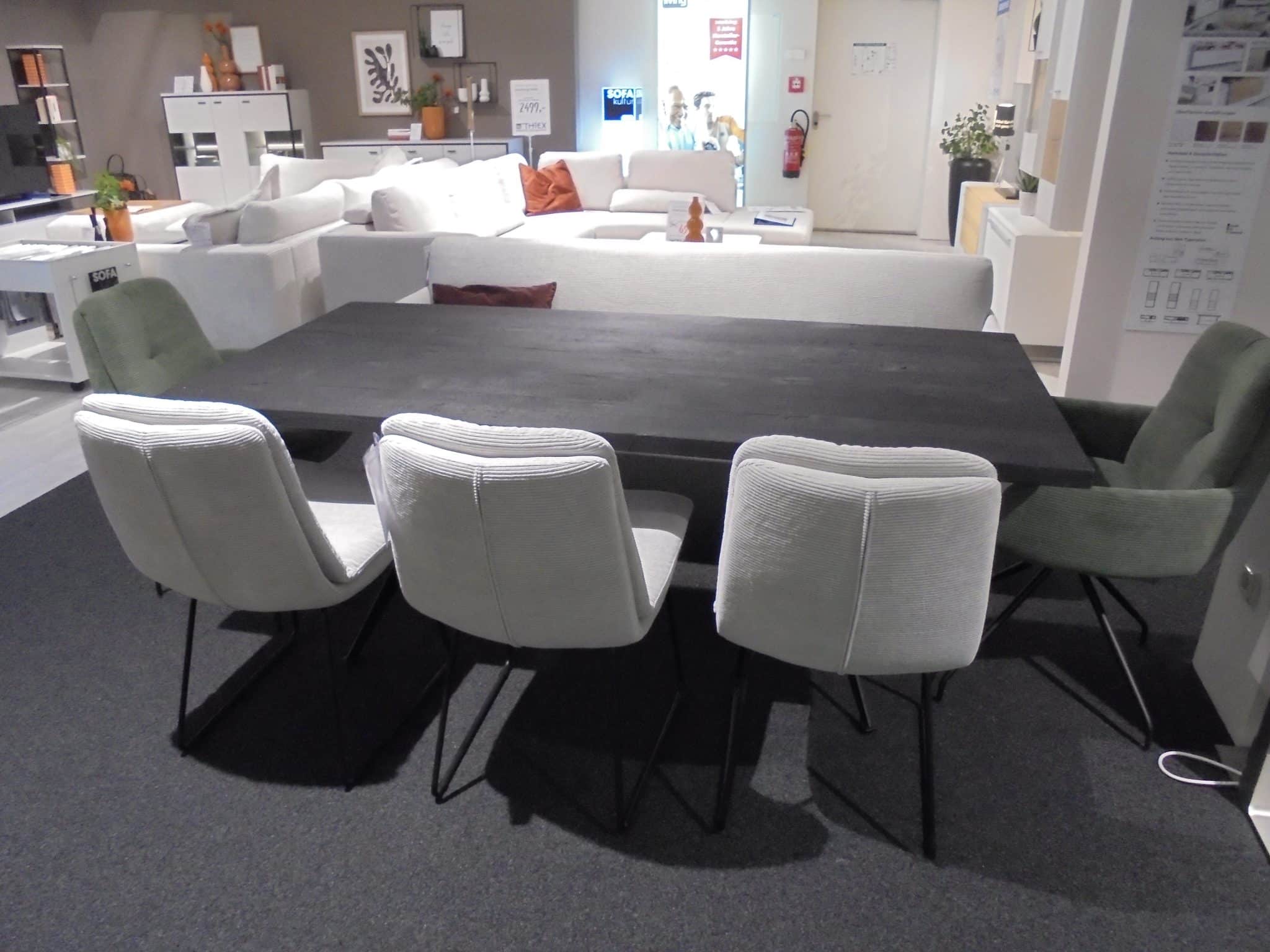 Die Bankgruppe Lungo/Biloxi/Major ist ein moderner schwarzer Esstisch mit sechs Stühlen, abgebildet mit Sofas und Dekor im Hintergrund.