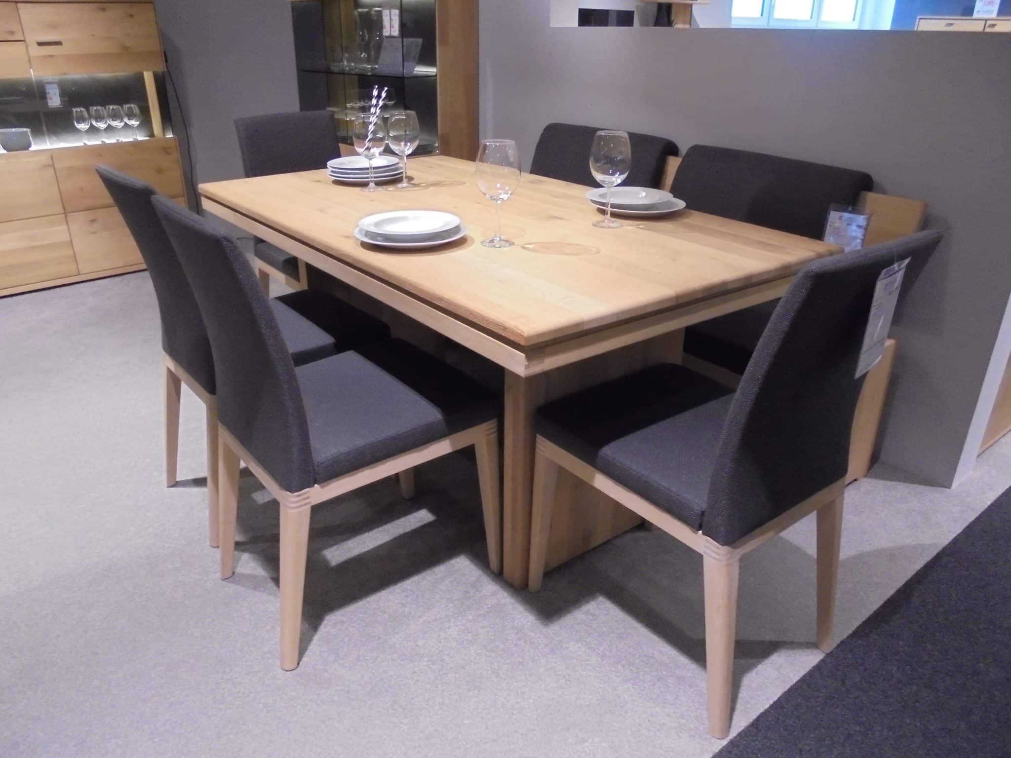 In der Bankgruppe Volterra Plus steht ein Holztisch mit sechs dunklen Stühlen, Tellern und Gläsern in einem modernen Esszimmer.