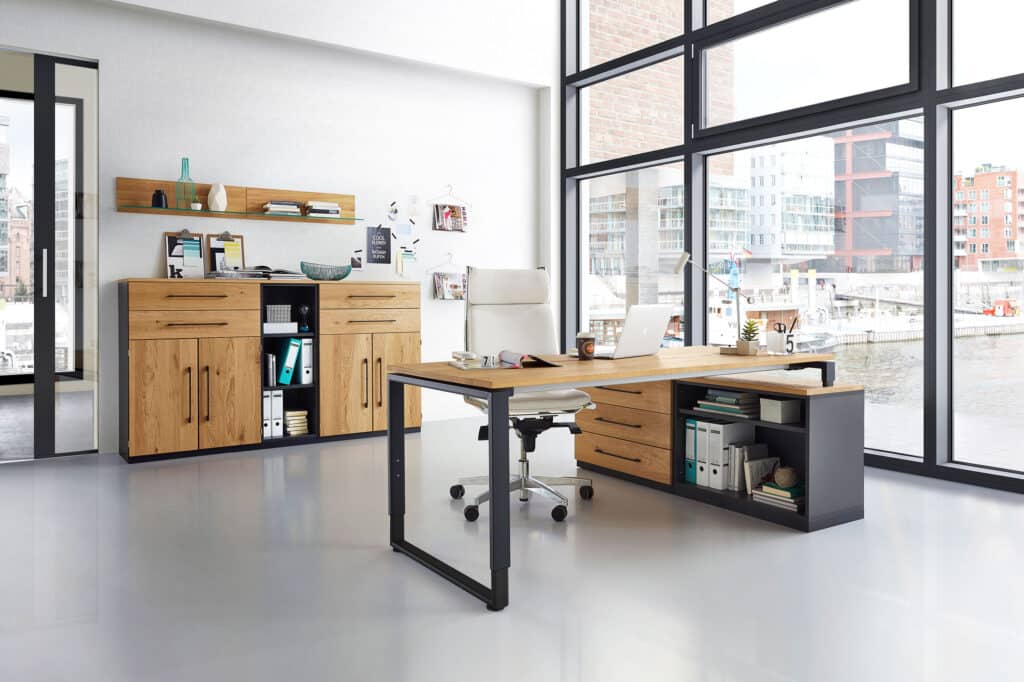 Modernes Büro mit großen Fenstern, Holzschreibtisch, Regalen, weißem Stuhl und Blick auf die Stadt draußen am Wasser.