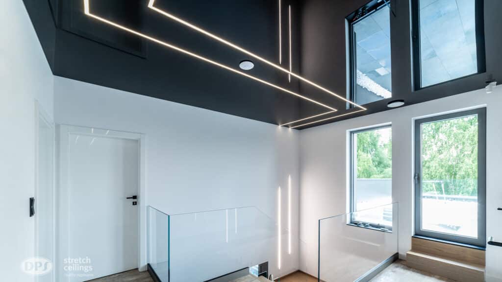 Modernes Interieur mit schwarzer Decke, linearen LED-Leuchten, großen Fenstern und Glastreppengeländer.