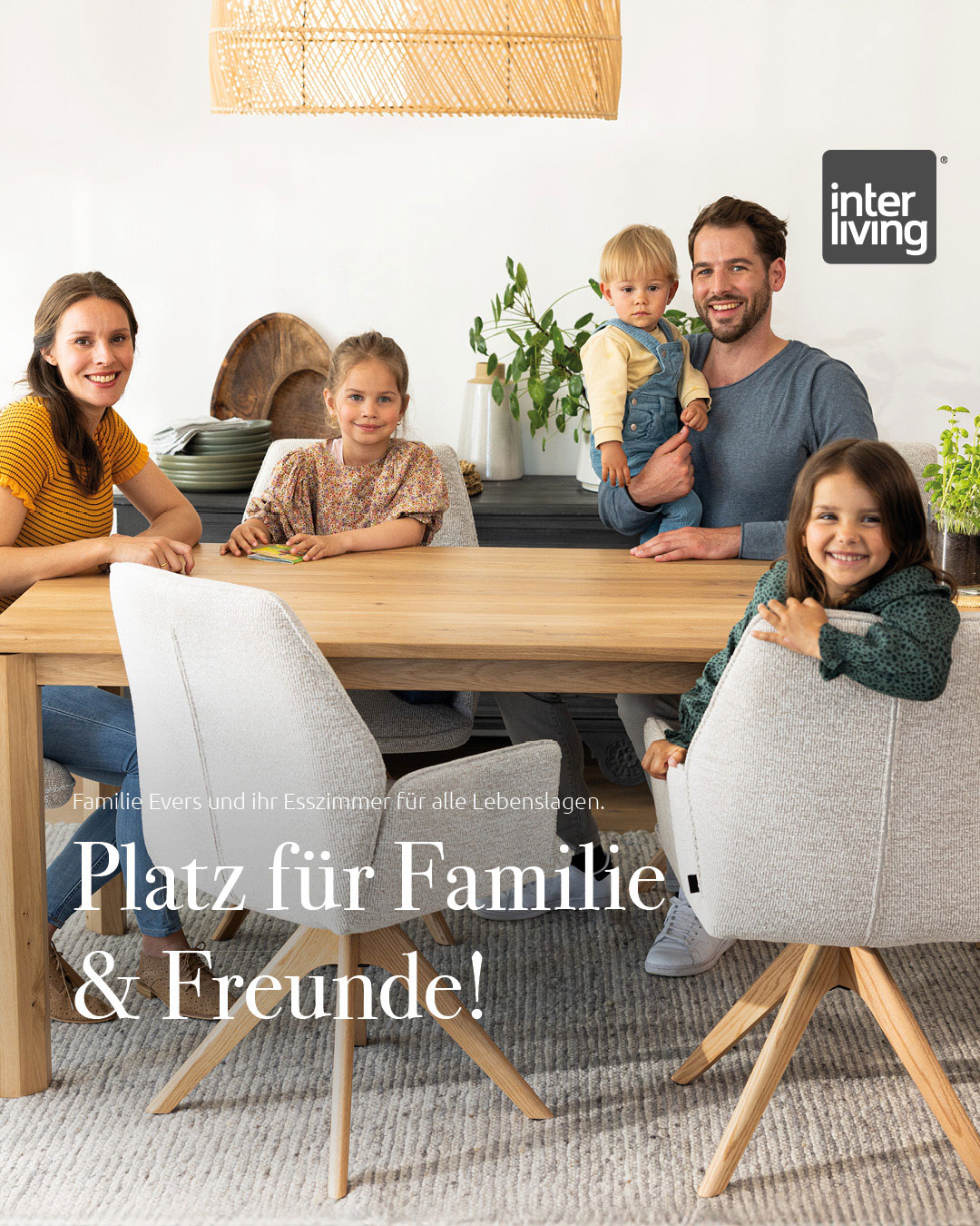 Eine fünfköpfige Familie lächelt um einen hölzernen Esstisch in einem hellen, modernen Esszimmer.