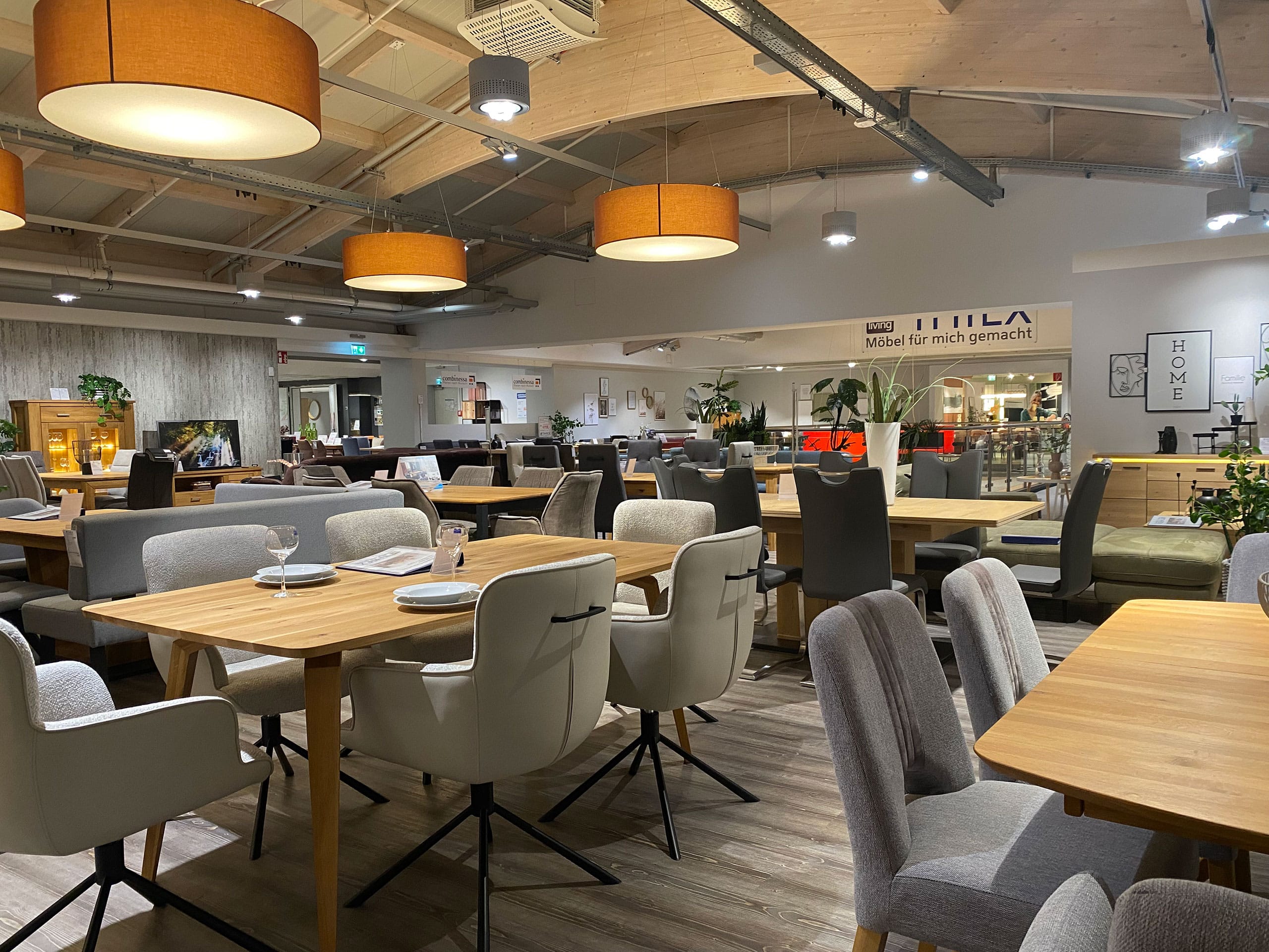 Die moderne Einrichtung des Restaurants mit Holztischen, gepolsterten Stühlen und warmer Beleuchtung schafft eine gemütliche, einladende Atmosphäre.