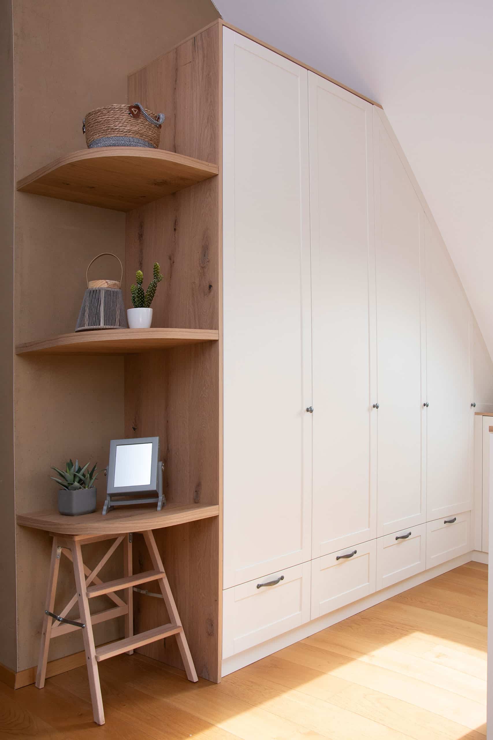 Moderner weißer Kleiderschrank mit offenen Holzregalen, einem kleinen Hocker, Topfpflanzen und Dekorationsartikeln in einem hellen Raum.
